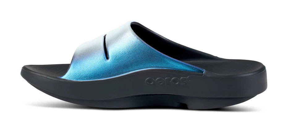 Women's Oofos Ooahh Luxe Slide. Light Blue upper. Black midsole. Medial view.